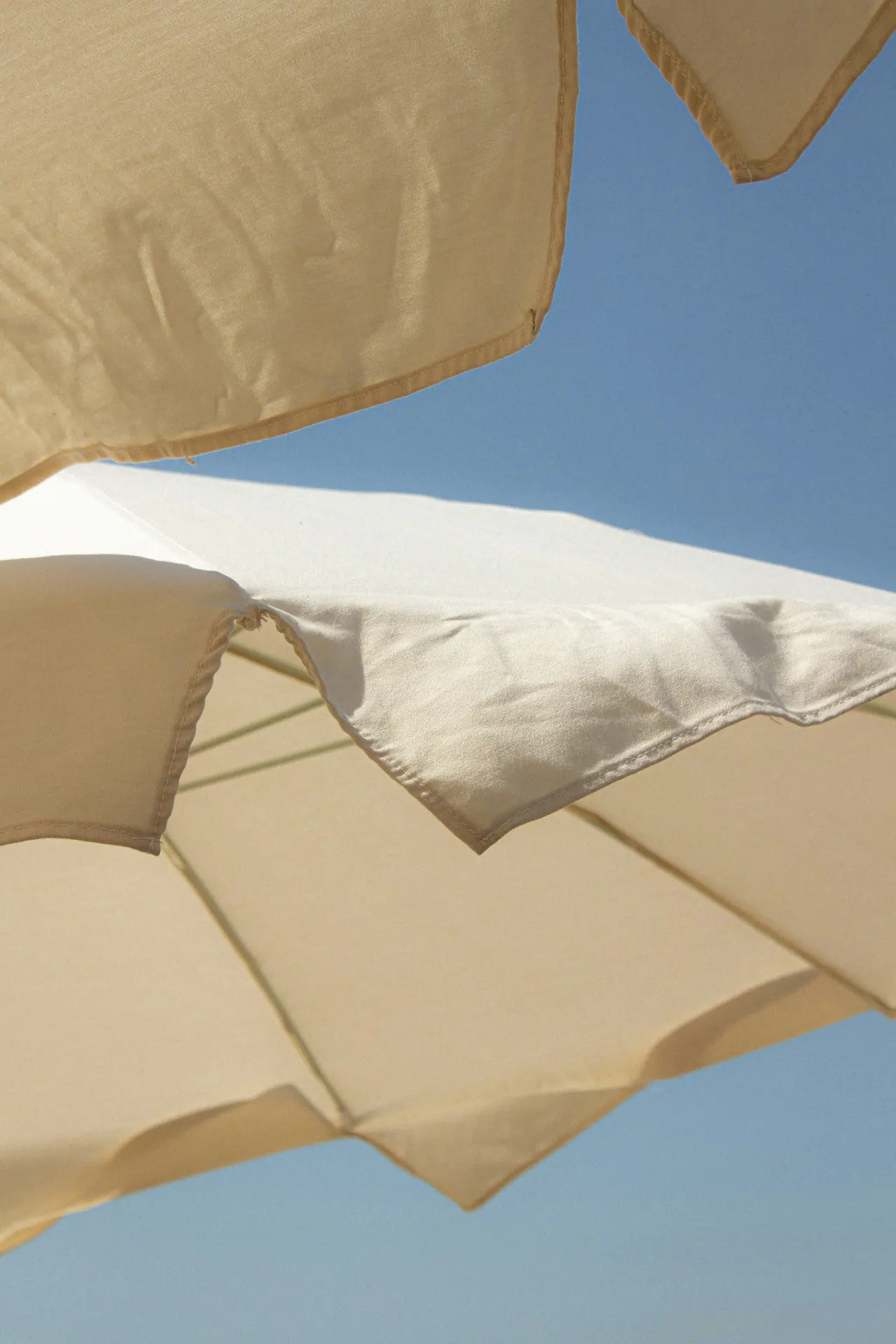 Neutral fabric canopies against a blue sky